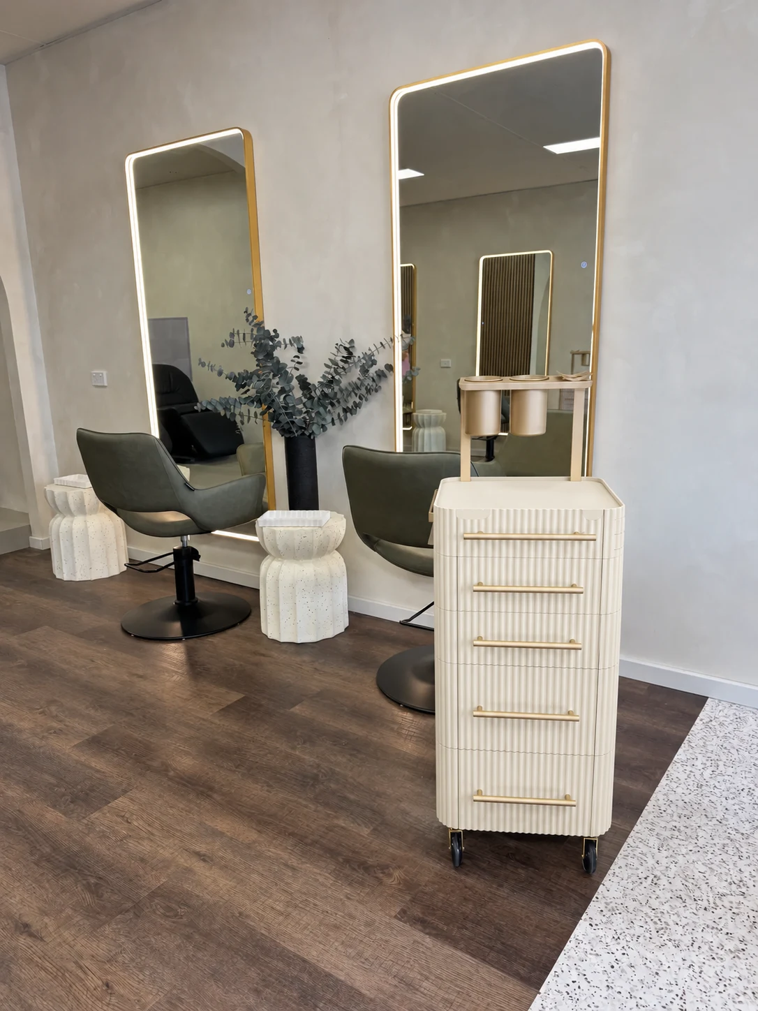 Ivory trolley beside styling chairs and illuminated mirrors